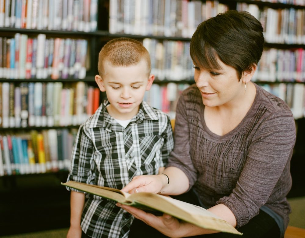 boy in gray sweater beside boy in gray and white plaid dress shirt